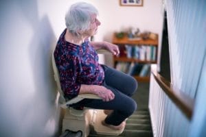 Seniorin überbrückt mit einem Sitzlift eine gerade Treppe